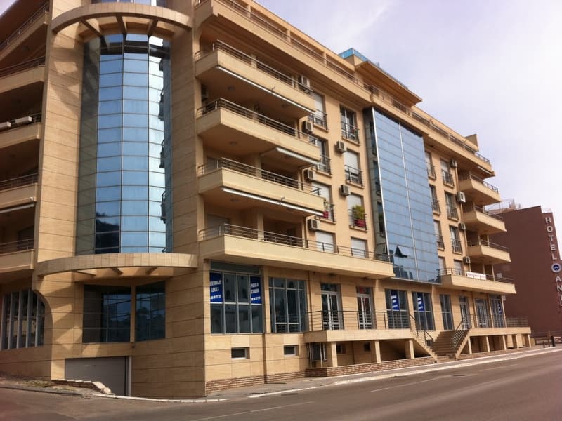 Современный жилой комплекс с панорамным остеклением и балконами в Бечичи, Черногория — фасад здания с коммерческими помеще...