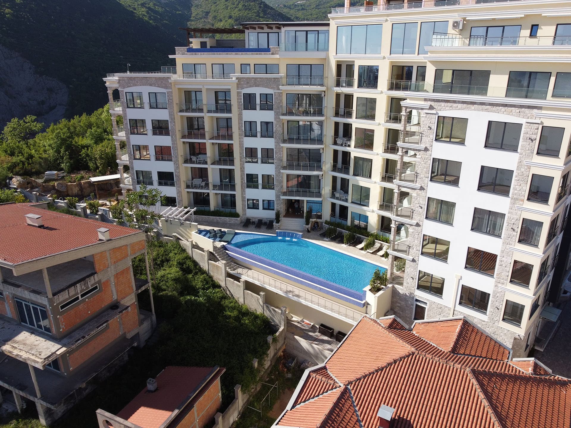 Жилой комплекс MonteDreams в Бечичи, Черногория: вид на современное здание с панорамными окнами и открытым бассейном.