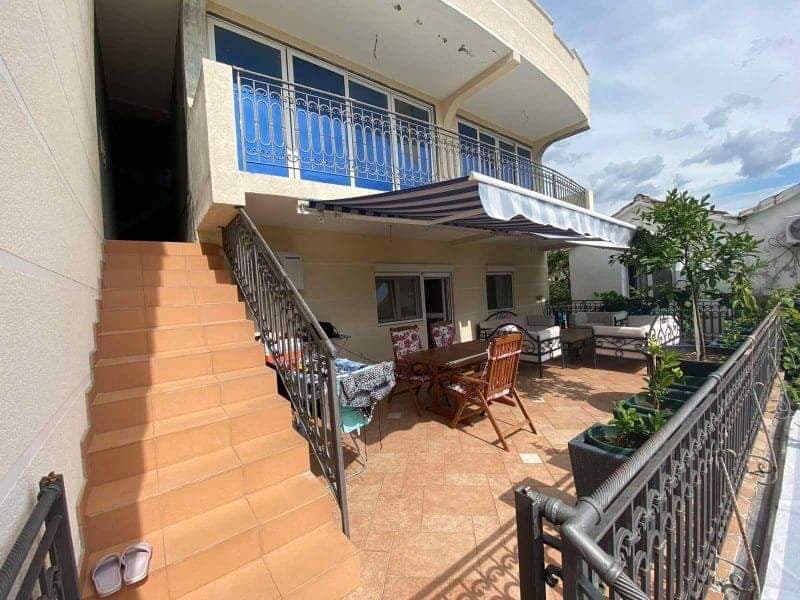 Терраса дома в Шушани, Черногория: обеденная зона, кованые перила, маркиза и лестница на второй этаж.