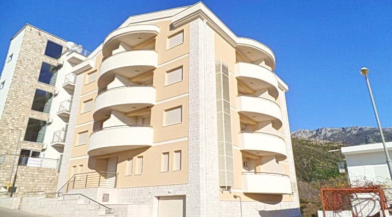 Современный жилой комплекс с полукруглыми балконами в Бечичи, Черногория: фасад отеля с отделкой камнем и светлой штукатуркой