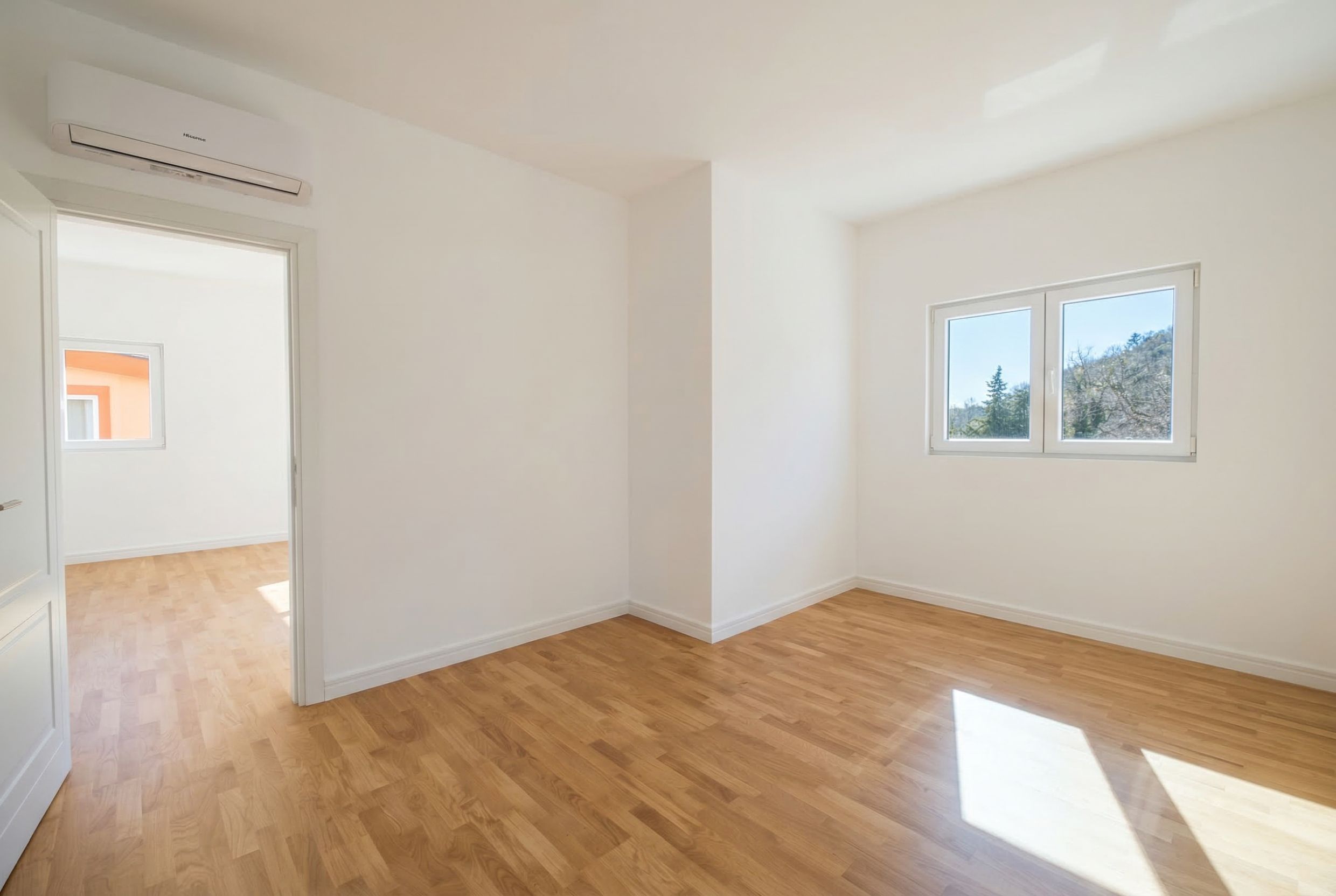 Bright bedroom with parquet flooring and air conditioning in an apartment for sale, Sutomore, Montenegro. View of nature from the window.