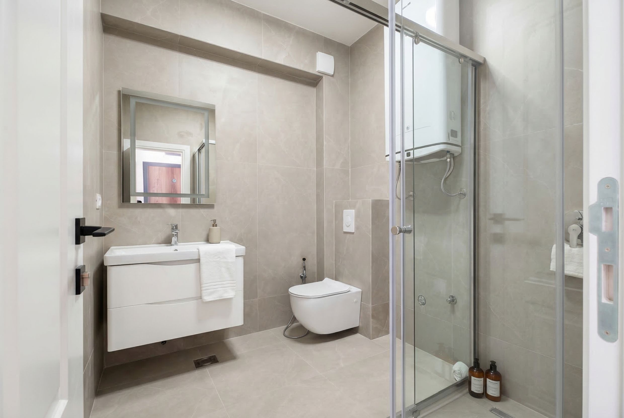 Modern bathroom with a walk-in shower in an apartment, Sutomore, Montenegro: light-colored tiles, wall-mounted sanitary ware.