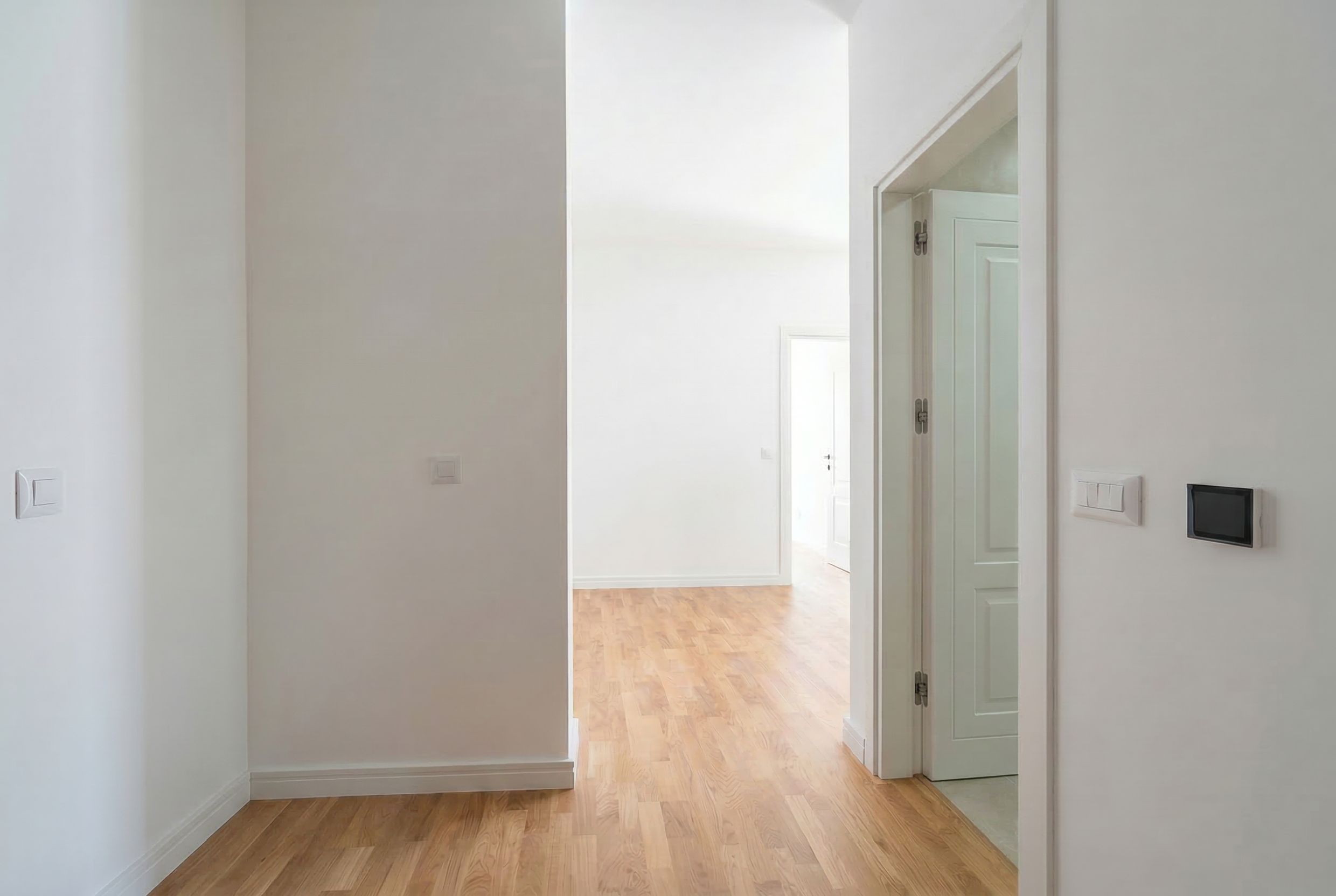Bright apartment interior in Sutomore, Montenegro: empty rooms with white walls, wooden floors, and interior doors.