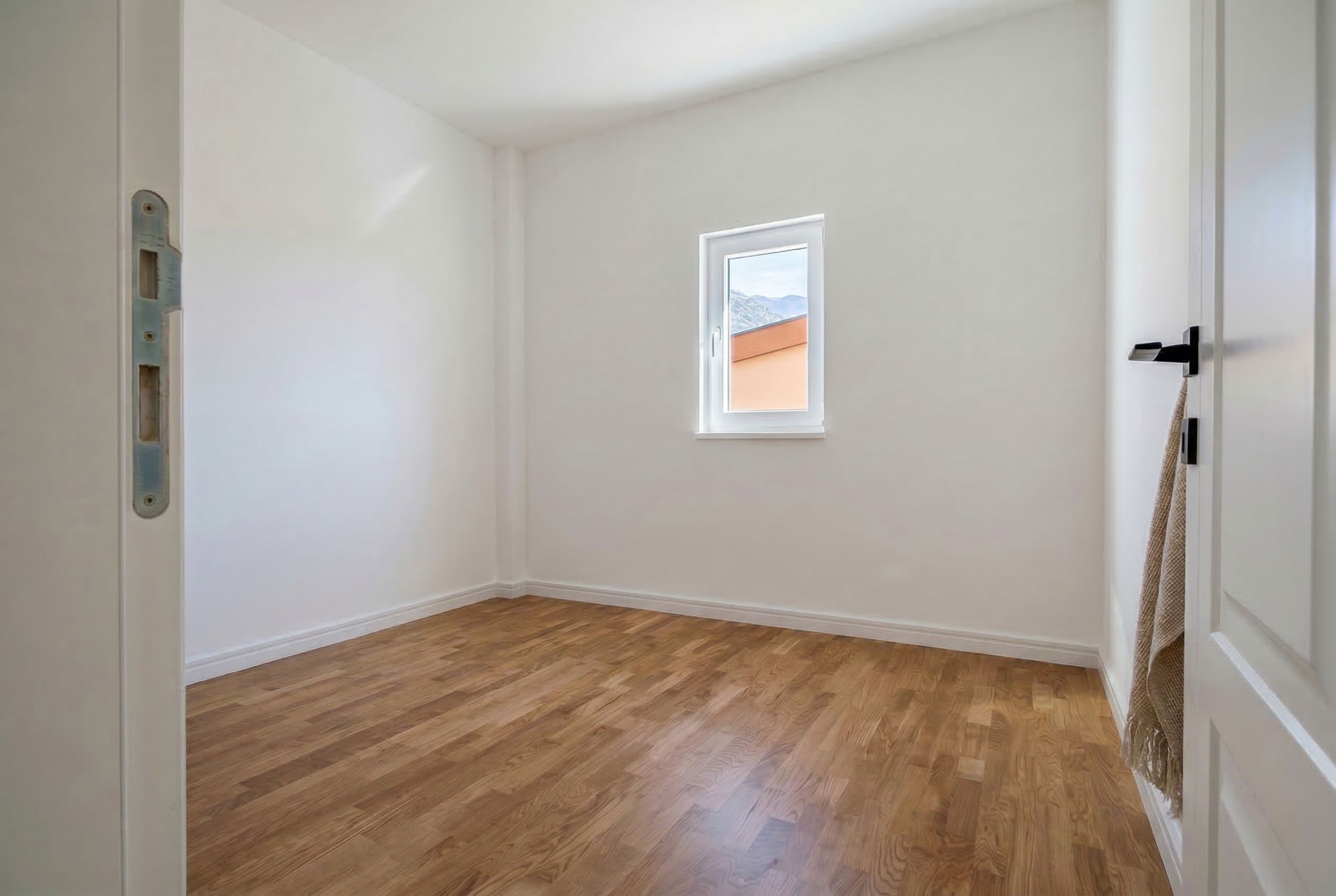 Bright empty bedroom with parquet flooring and mountain views in an apartment, Sutomore, Montenegro.