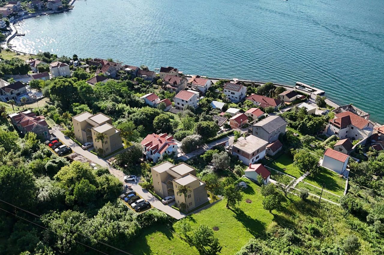 Aerial view of modern residential buildings in Stoliv, Montenegro, with panoramic views of the Bay of Kotor and greenery.