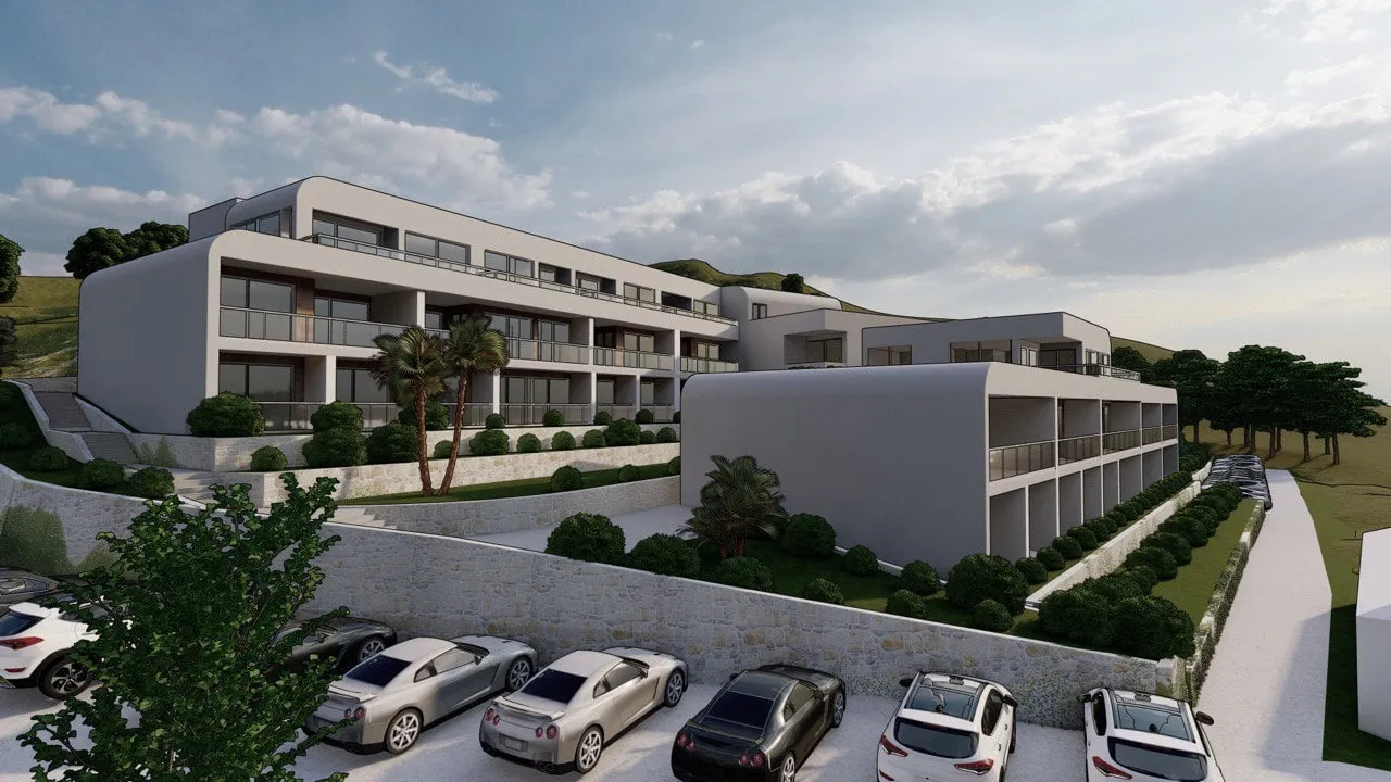Exterior view of a modern multi-story residential complex with balconies and a parking area in the foreground.