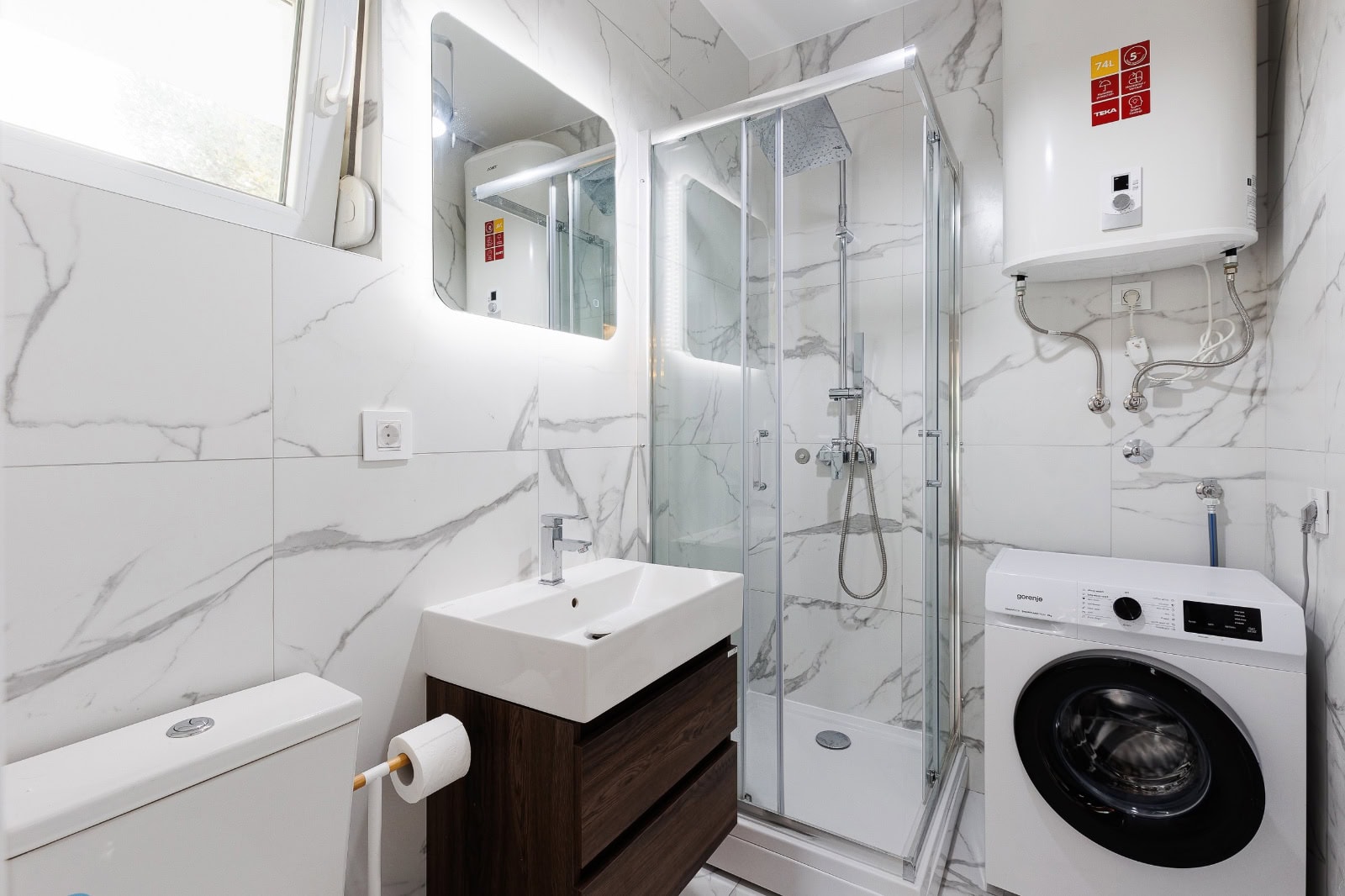 Modern bathroom with a shower cabin and washing machine in an apartment, Becici, Montenegro.