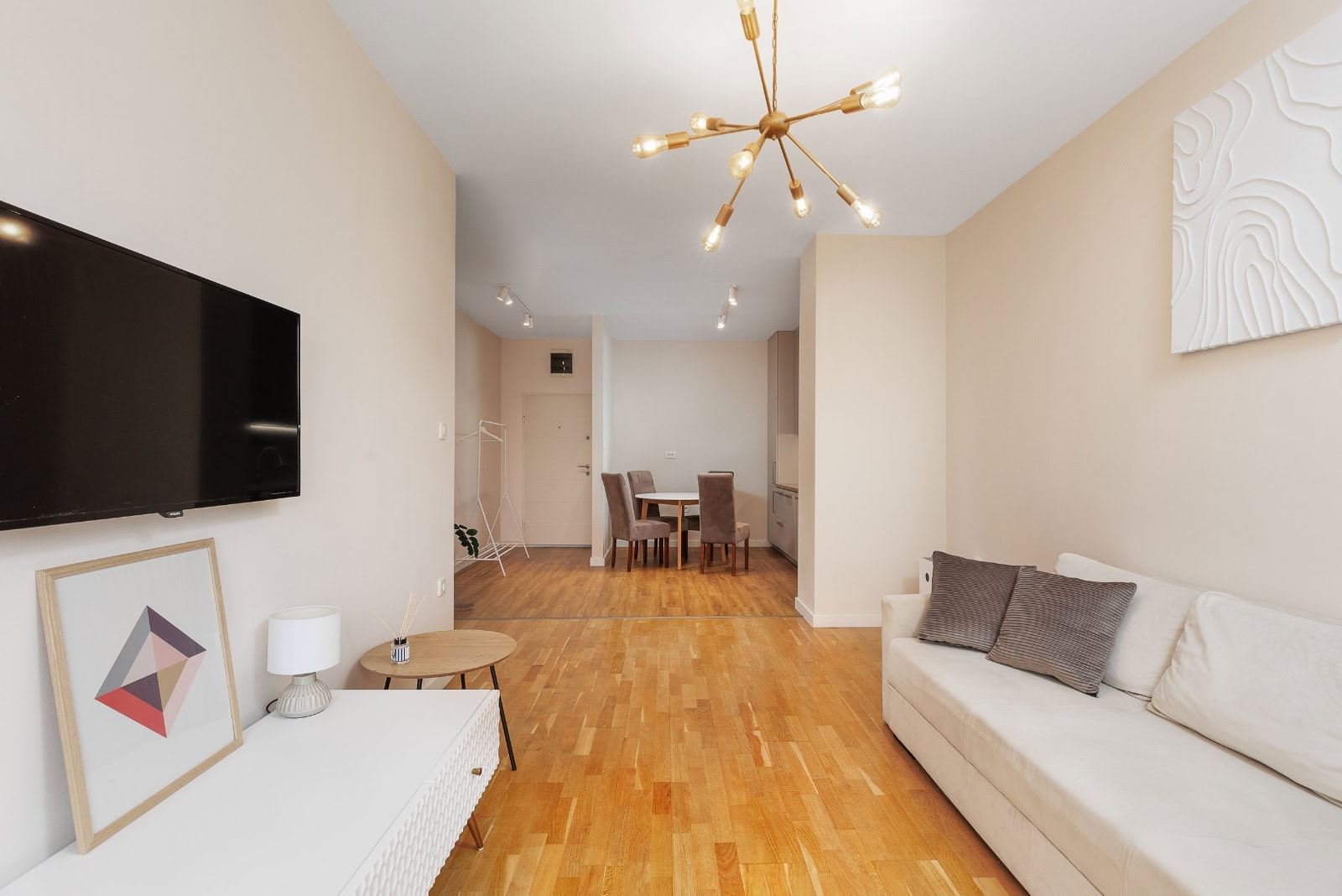 Bright living room in an apartment in Bečići, Montenegro: modern furniture, designer chandelier, and parquet flooring.