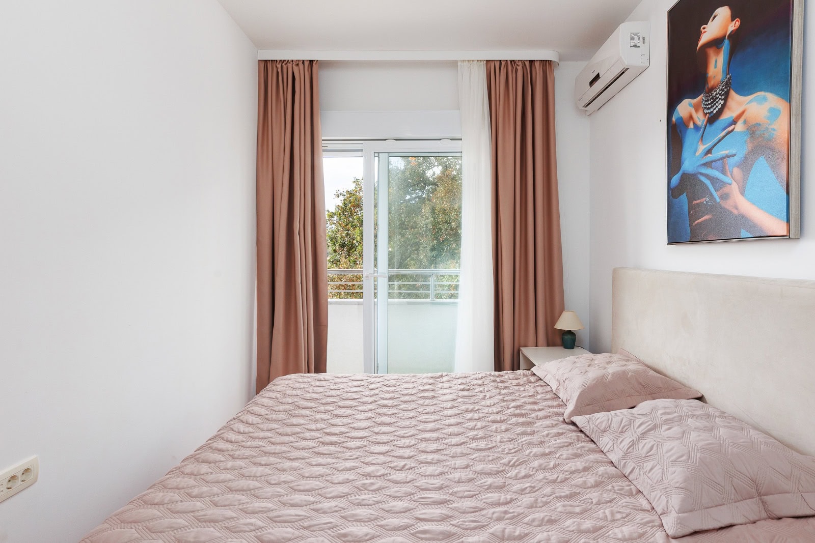 Cozy bedroom with a double bed and access to the balcony in an apartment, Bečići, Montenegro. Modern interior.