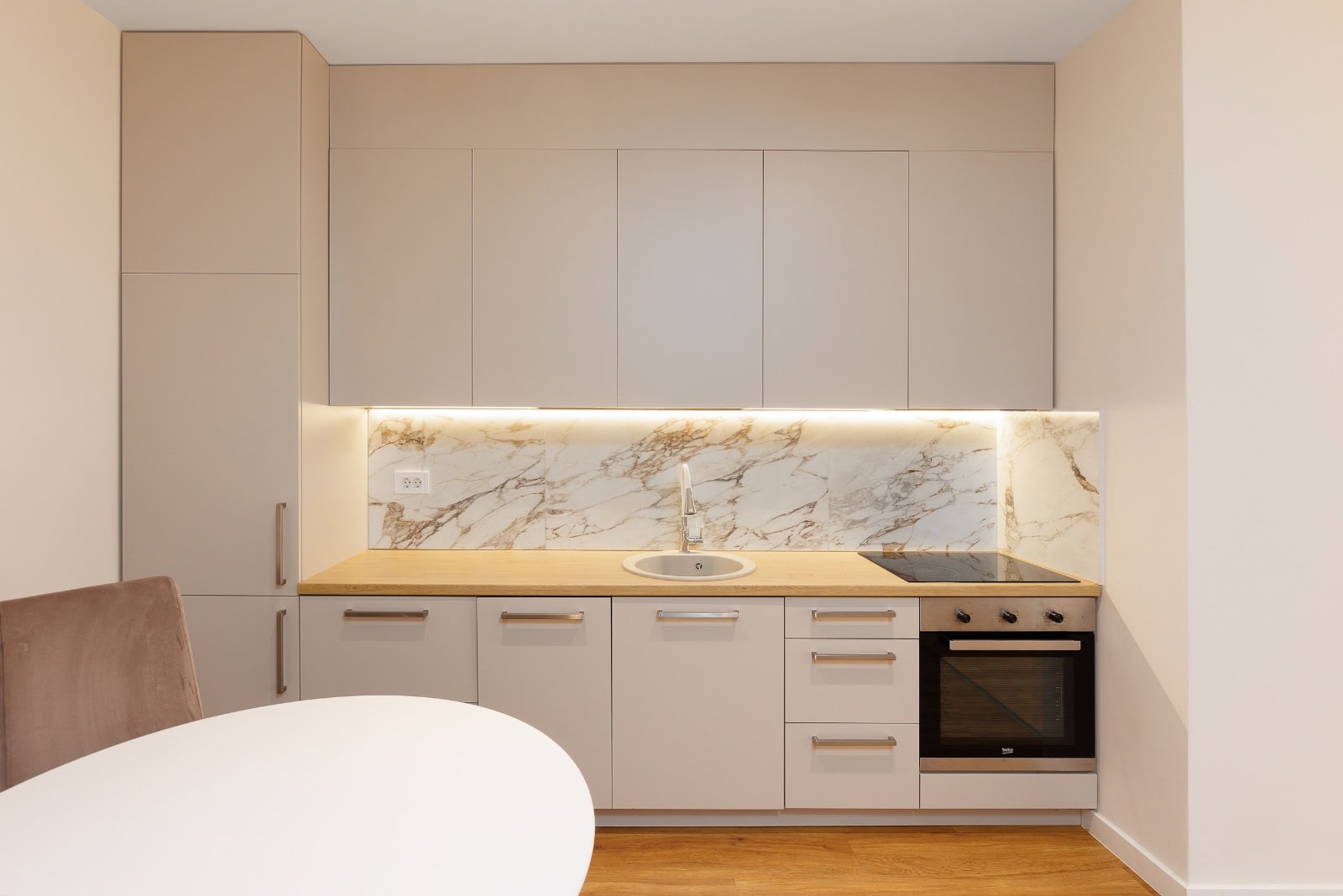 Modern kitchen in an apartment in Bečići, Montenegro: beige cabinets, marble-look backsplash, built-in appliances, and lighting.