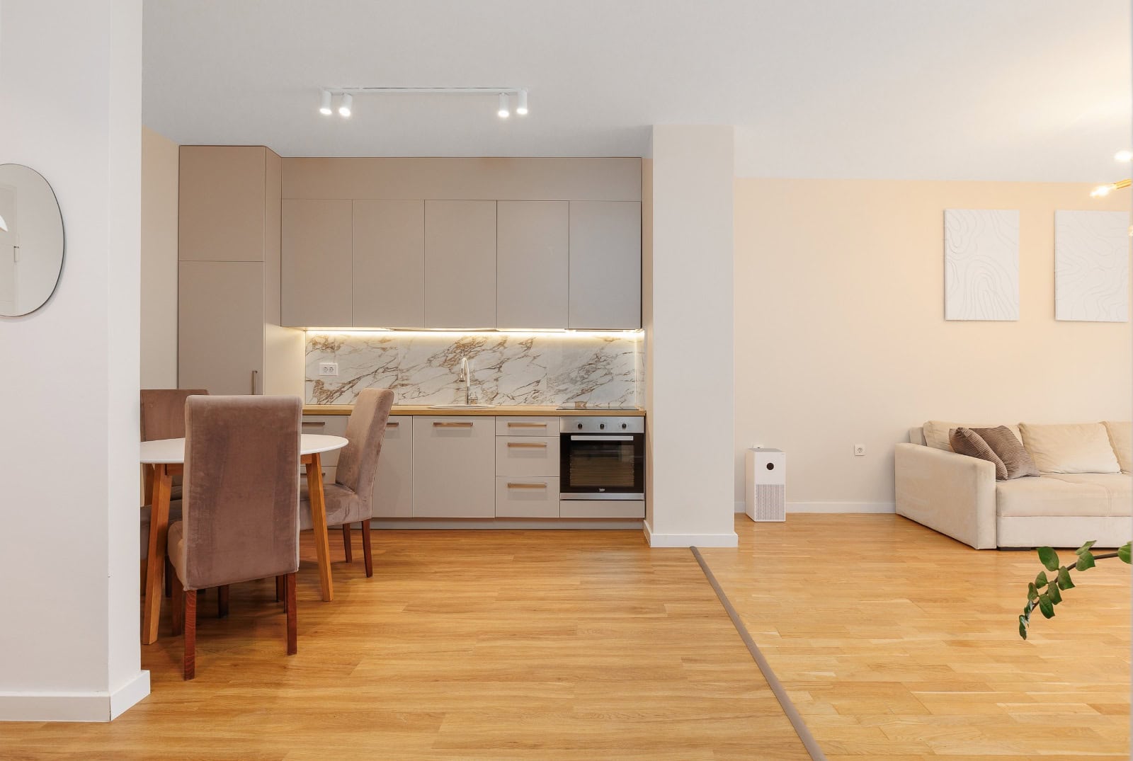 Modern kitchen-living room in an apartment in Bečići, Montenegro: beige cabinetry, marble backsplash, and dining area.