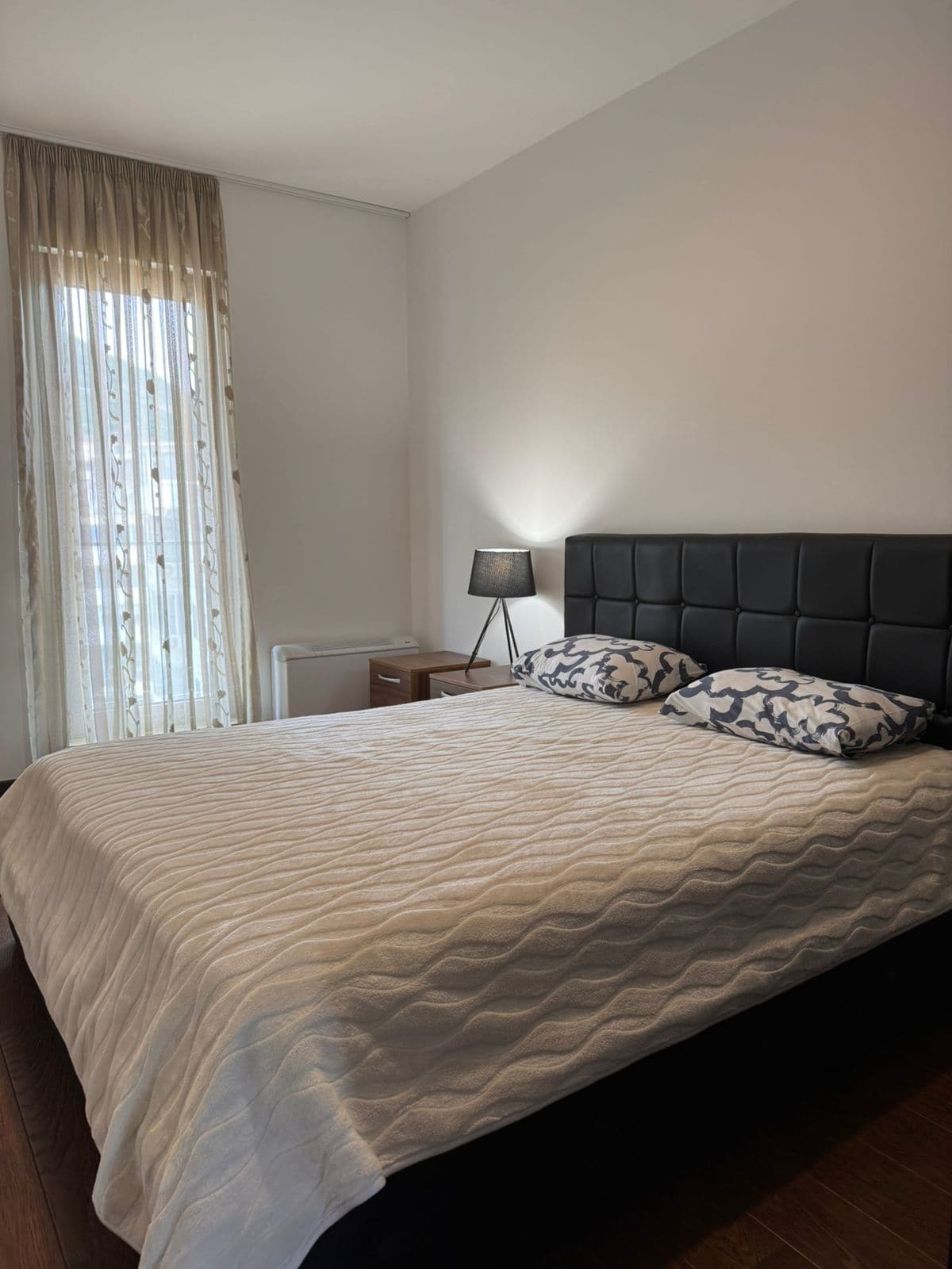 Cozy bedroom with a double bed in an apartment in Budva, Montenegro: modern furniture and a panoramic window.