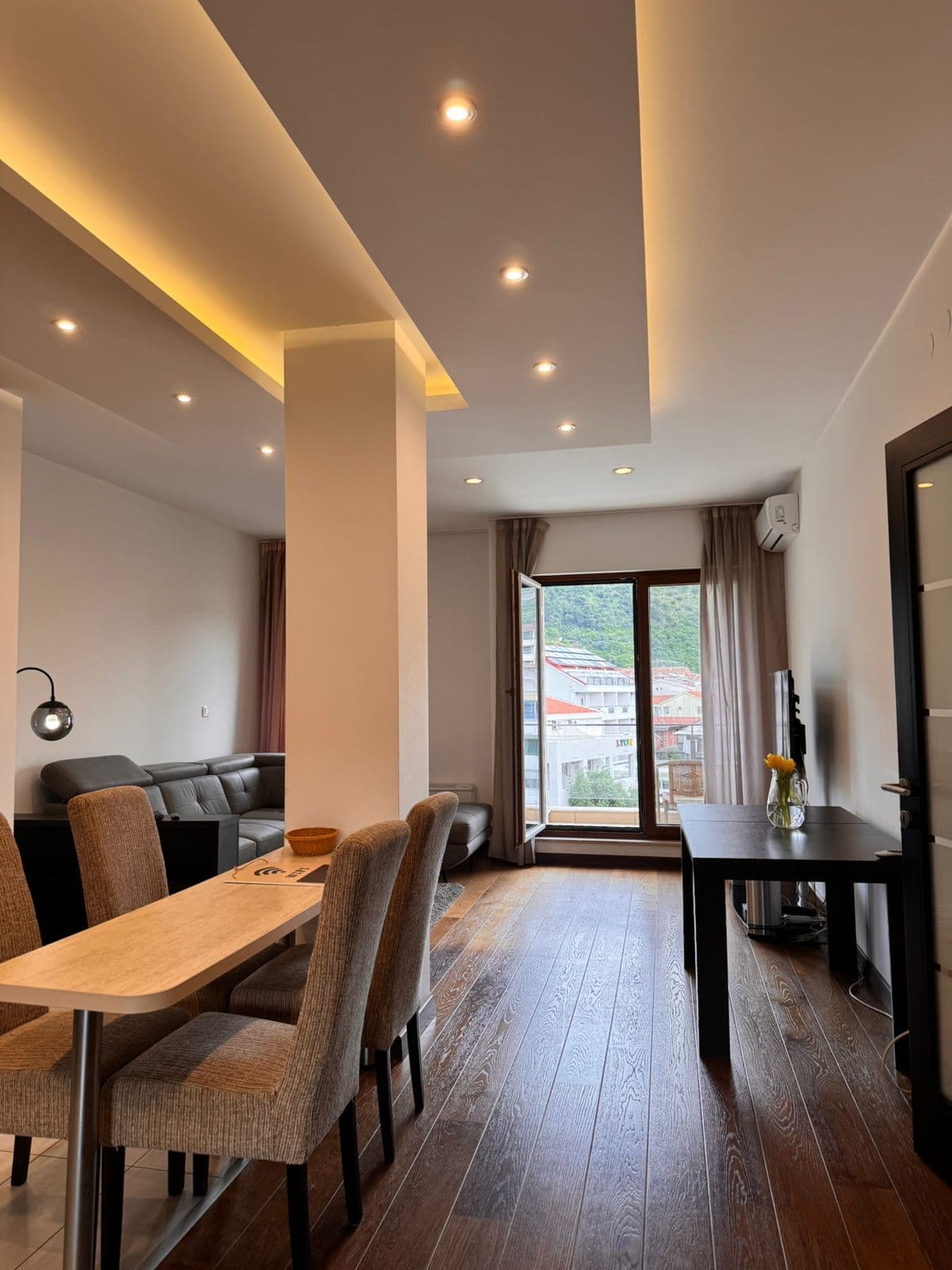 Modern living room in an apartment in Budva, Montenegro: dining area, leather sofa, recessed lighting, and mountain view.