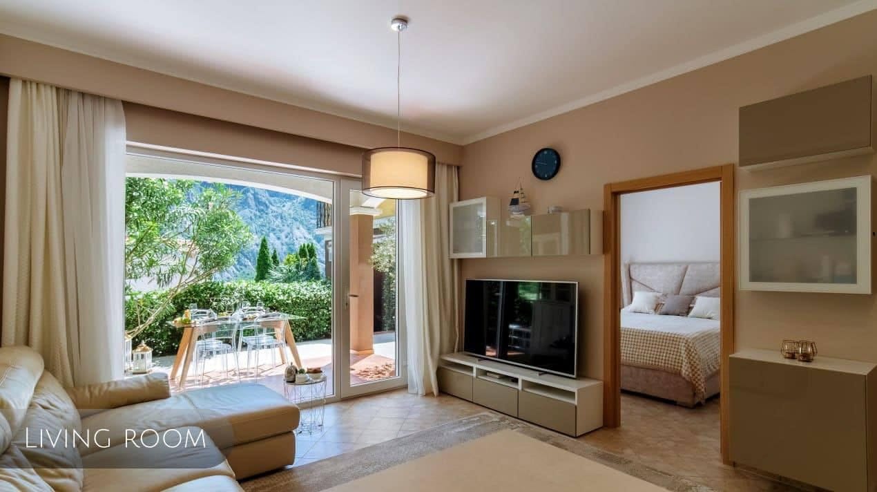 Bright living room in an apartment, Orahovac, Montenegro: modern furniture, TV area, and access to a terrace with mountain views.