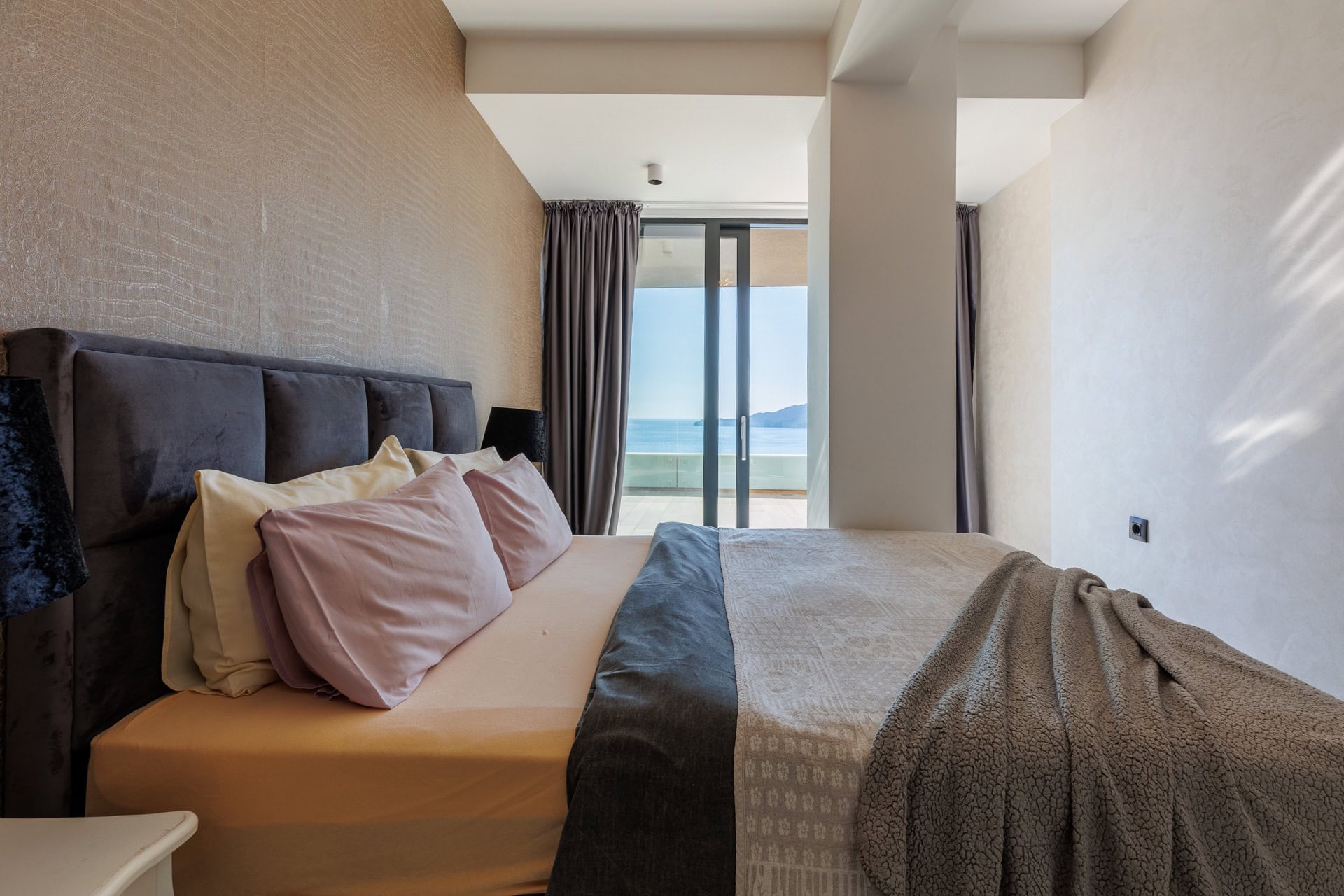 Bedroom in a modern apartment in Bečići, Montenegro: a double bed, stylish interior, and sea view from the terrace.