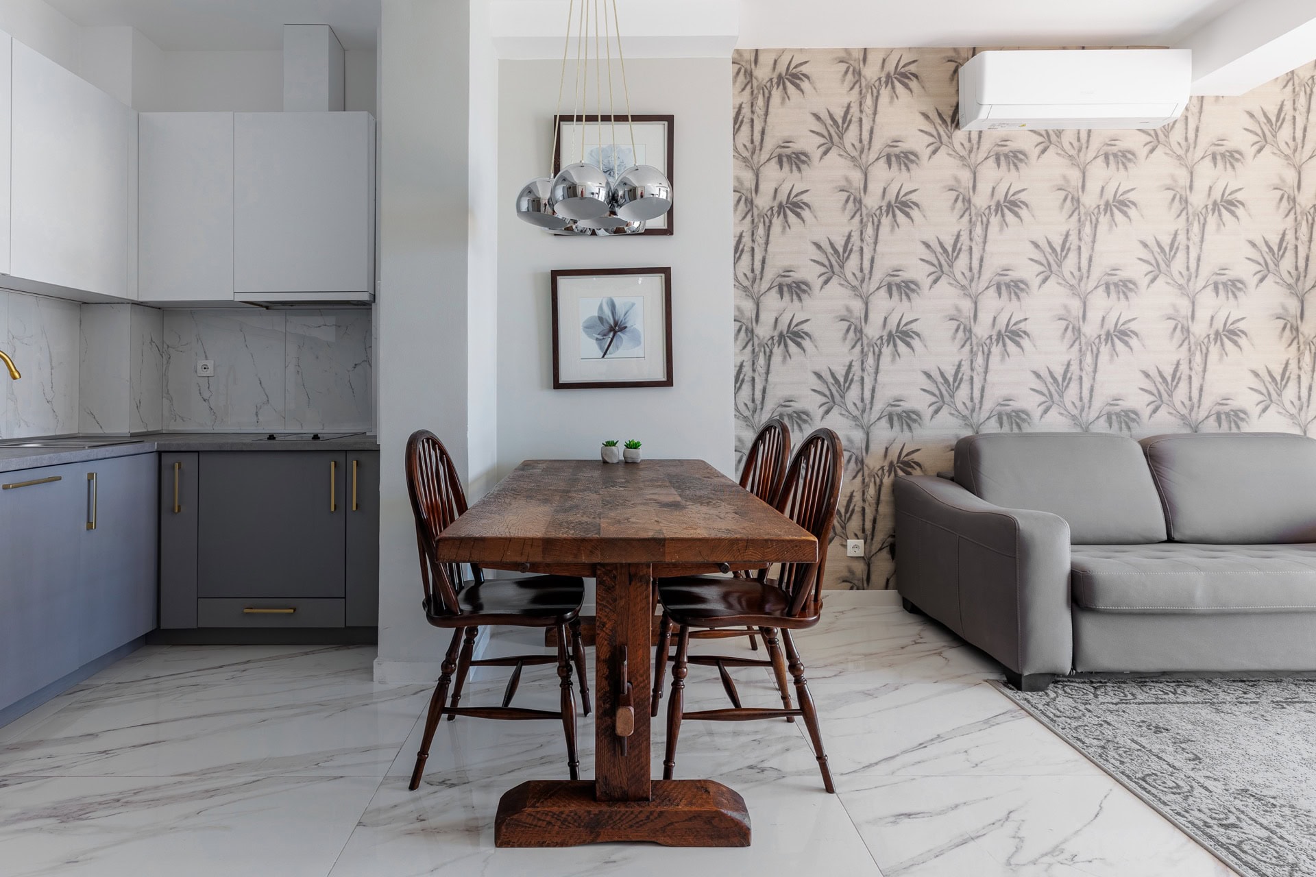 Modern living room with kitchen in an apartment, Bečići, Montenegro: wooden dining table, gray sofa, and stylish decor.
