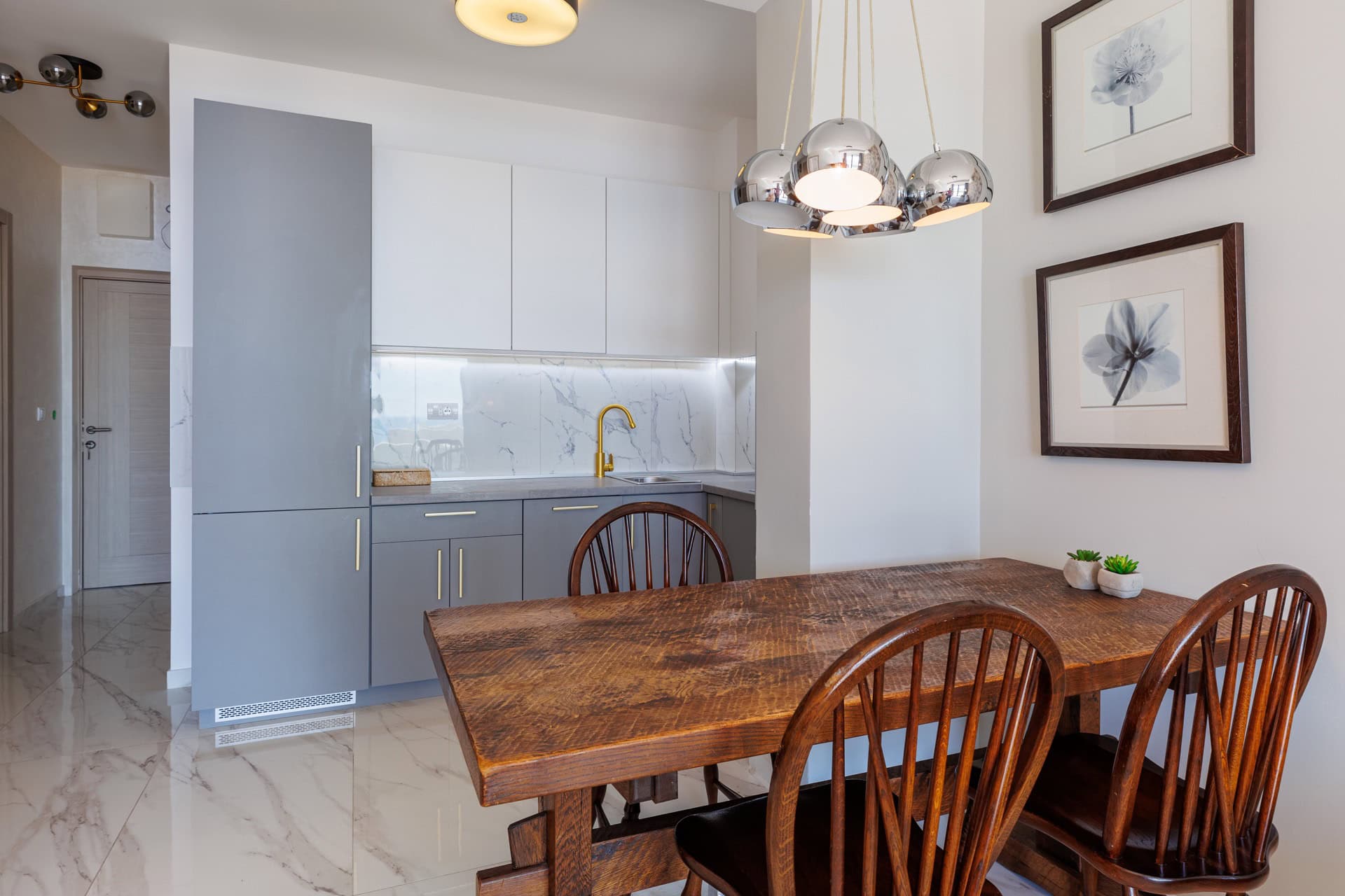 Modern kitchen in an apartment in Bečići, Montenegro: gray cabinets, marble backsplash, and a wooden dining table.