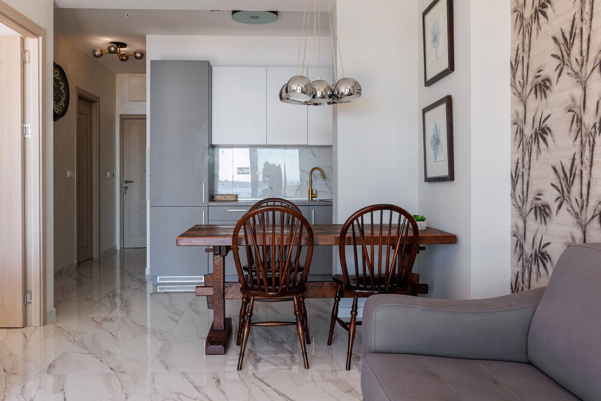 Modern kitchen-living room in an apartment in Bečići, Montenegro: wooden table, stylish cabinetry, and marble floor.