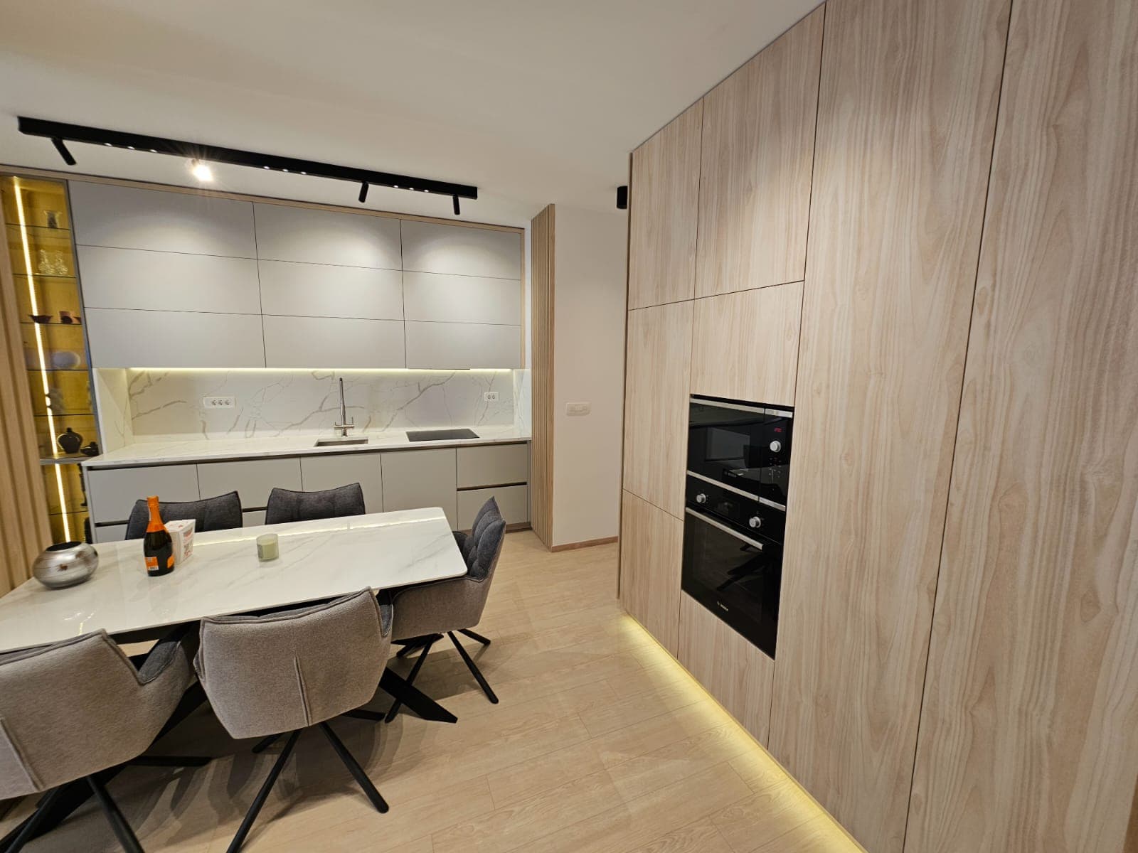 Modern kitchen-dining room in an apartment, Budva, Montenegro: light-colored cabinetry, built-in appliances, and a dining area.