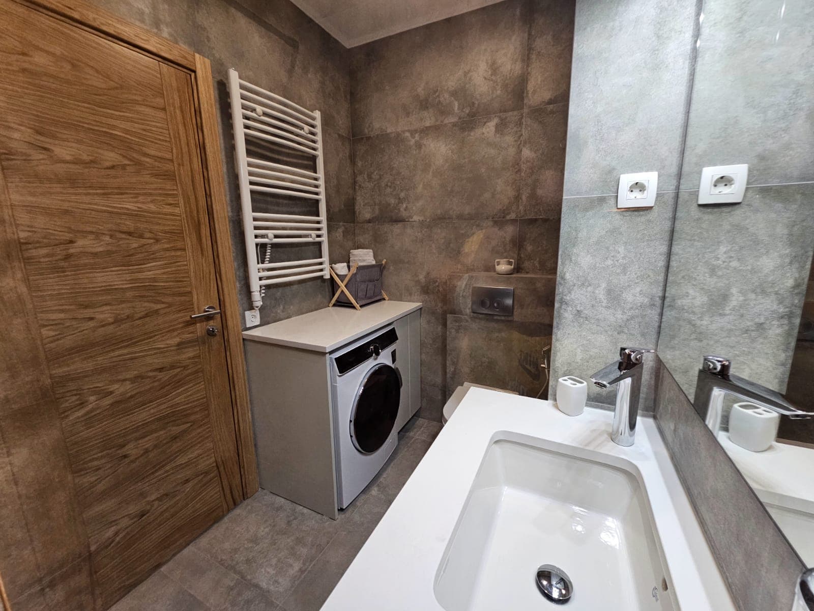 Modern bathroom in an apartment in Budva, Montenegro: stylish finishes, built-in washing machine, and sink.