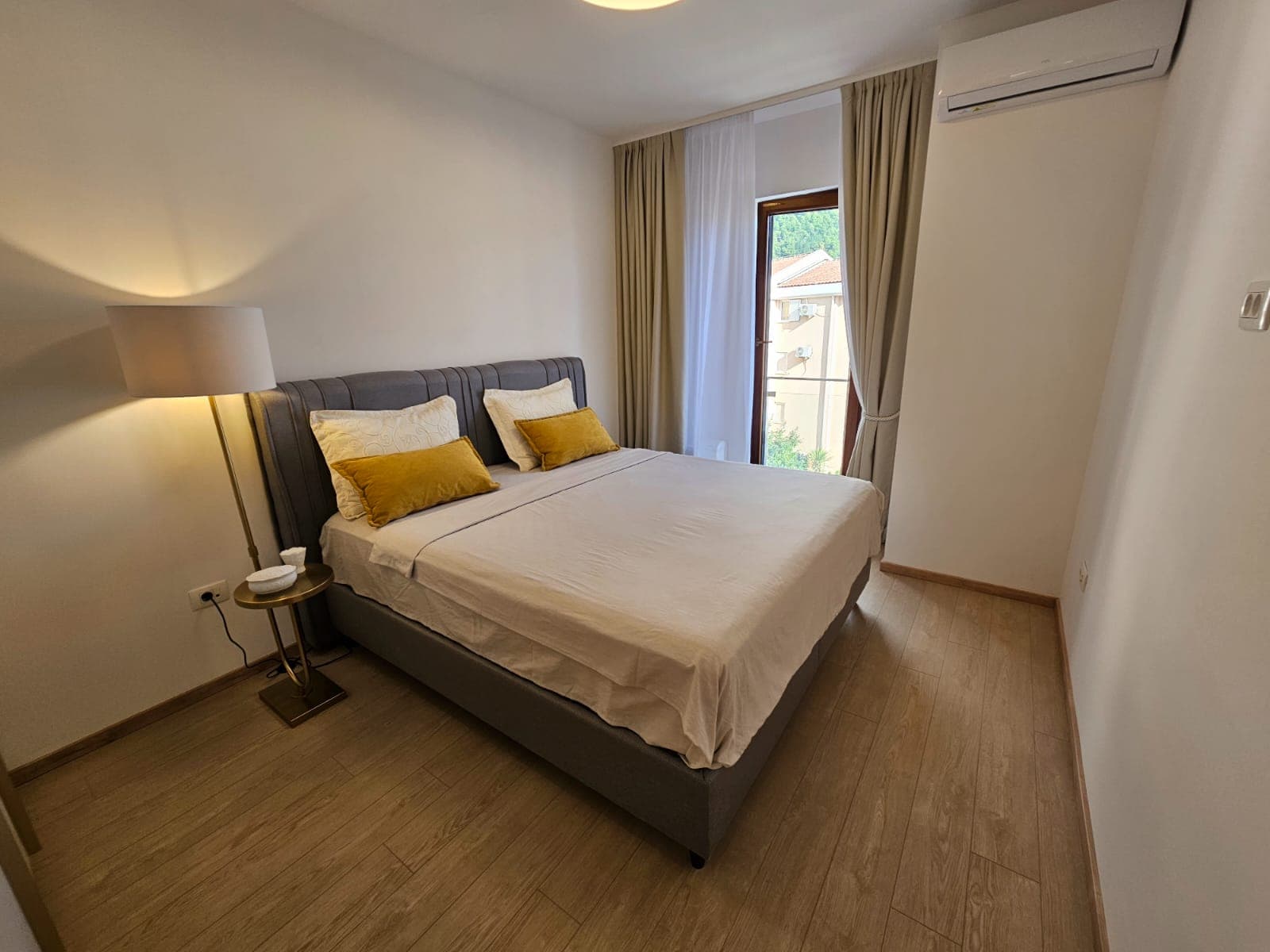 Cozy bedroom with a double bed in an apartment in Budva, Montenegro: bright interior, laminate flooring, and air conditioning.