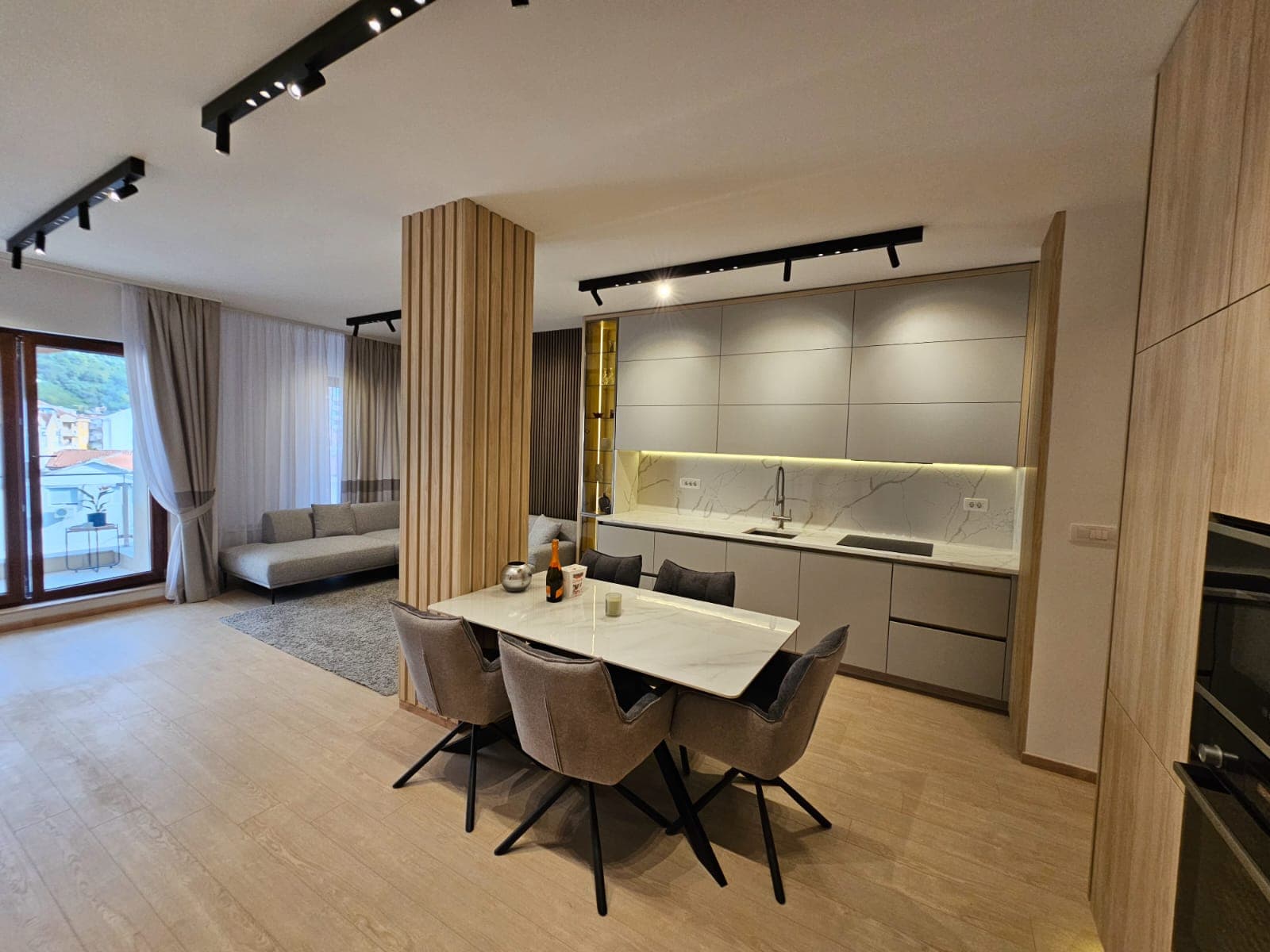 Modern kitchen-living room in an apartment, Budva, Montenegro: stylish cabinetry, dining area, and panoramic windows.