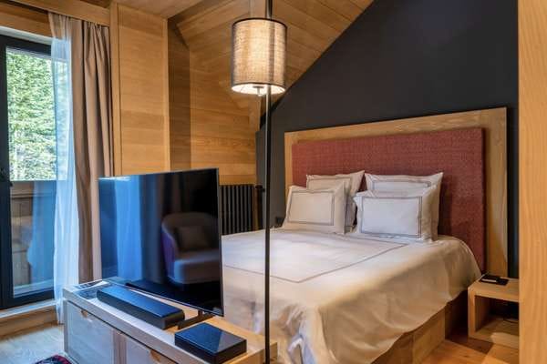 Cozy modern-style bedroom with wood finishes in the Kolashin residential complex, Montenegro: a double bed and TV area.