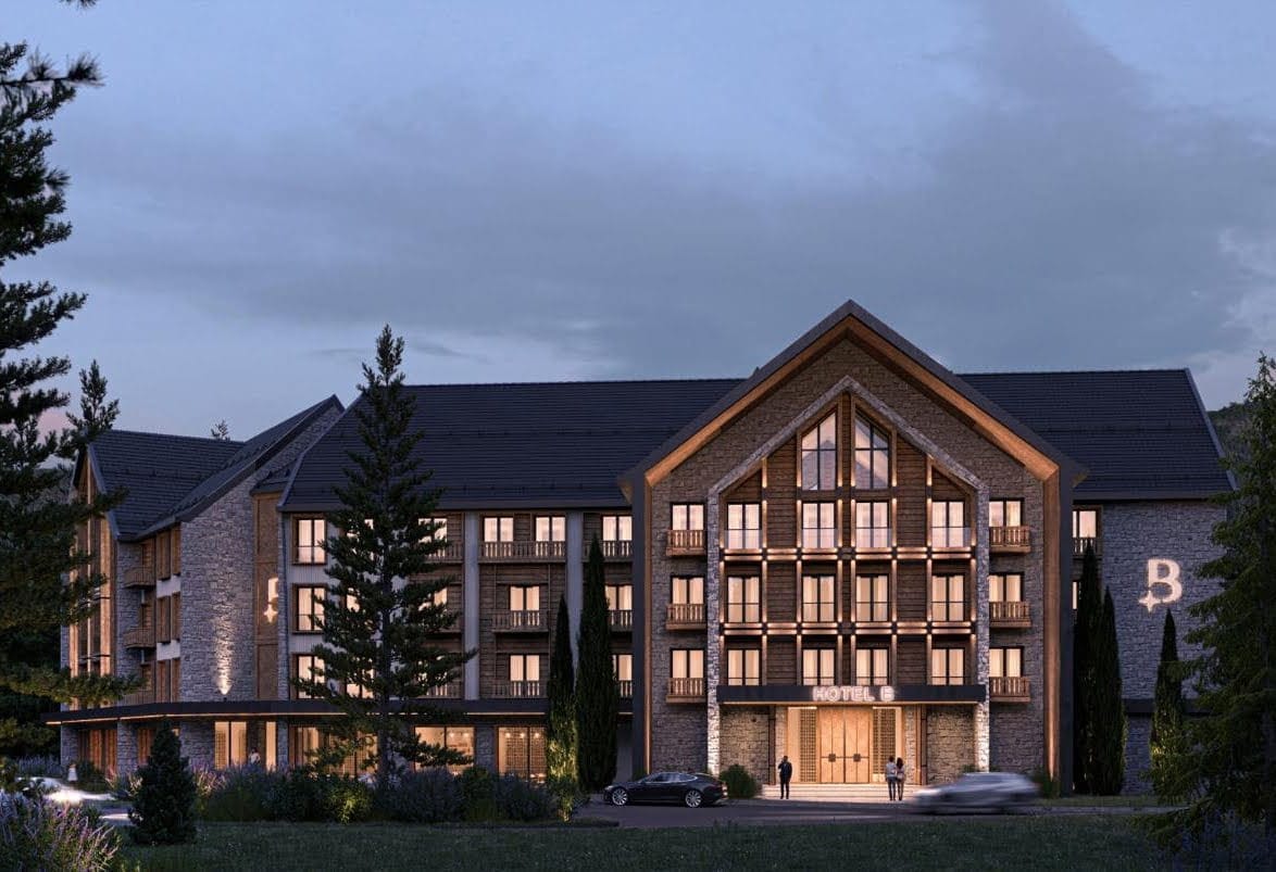 Modern chalet-style hotel with stone and wood finishes in Kolašin, Montenegro: exterior view in the evening.