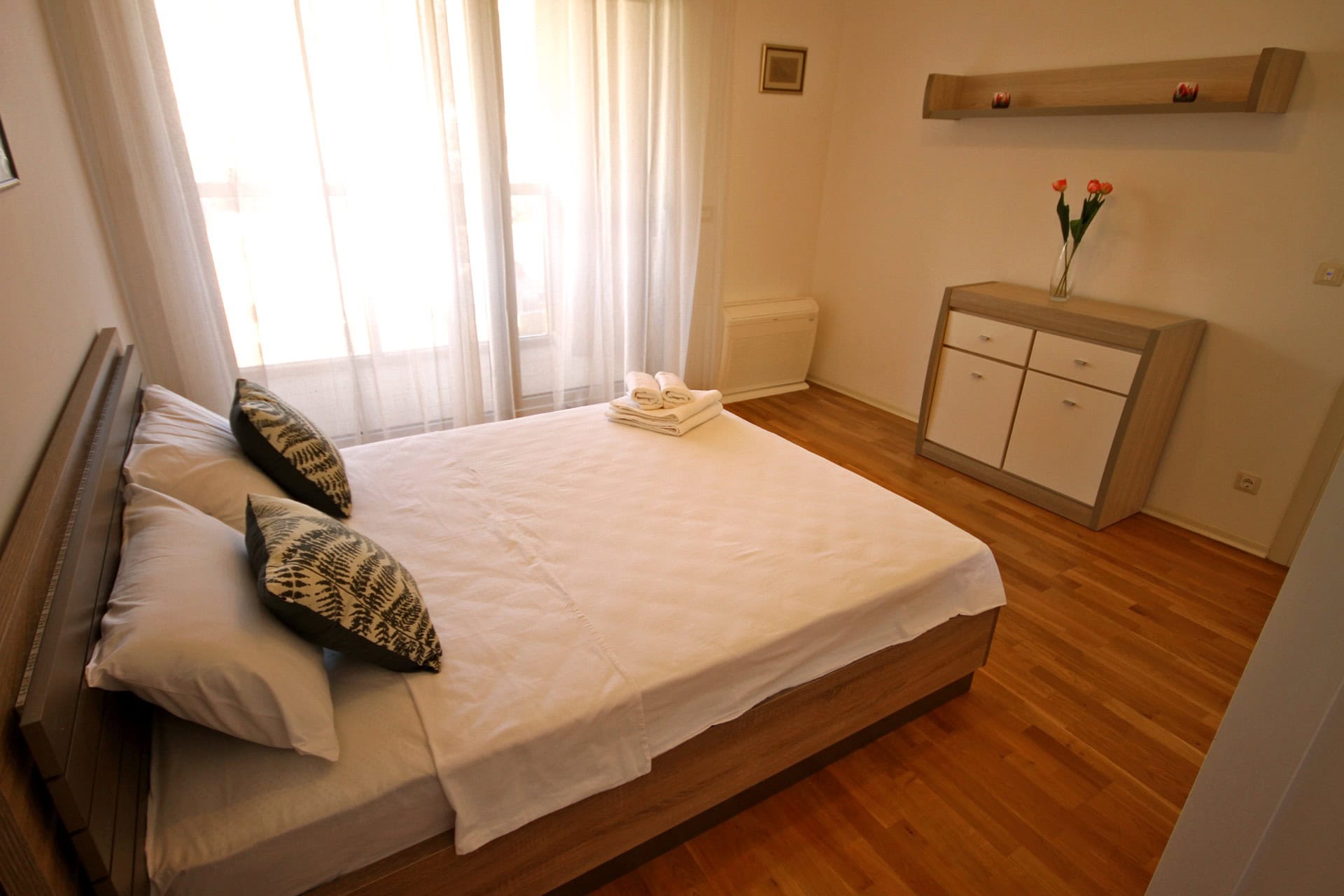 Cozy bedroom with a double bed and parquet flooring in an apartment in Budva, Montenegro. Bright interior with a dresser.