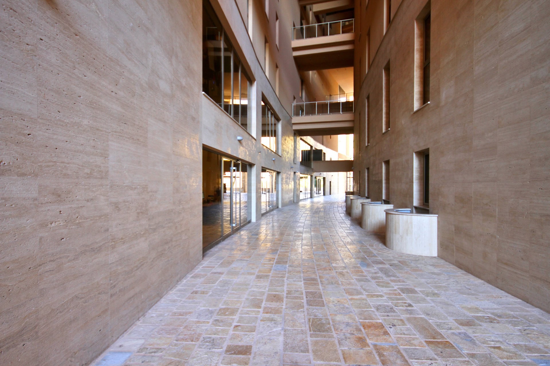 Modern residential complex in Budva, Montenegro: interior gallery with natural stone finishes and panoramic windows