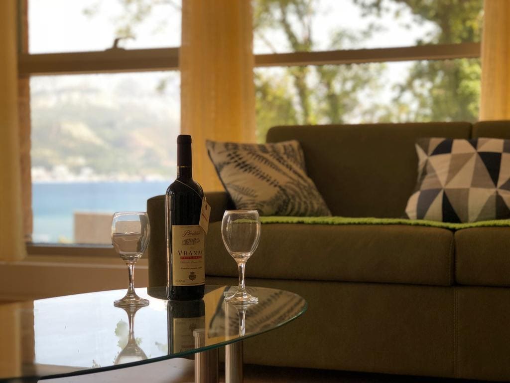 Living room in an apartment in Budva, Montenegro: sea view, a soft sofa, a glass table with wine and glasses.