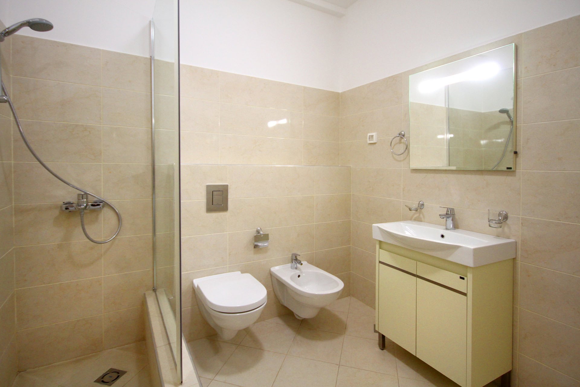 Modern bathroom in an apartment in Budva, Montenegro: shower cabin, wall-hung toilet, bidet, and vanity with sink.