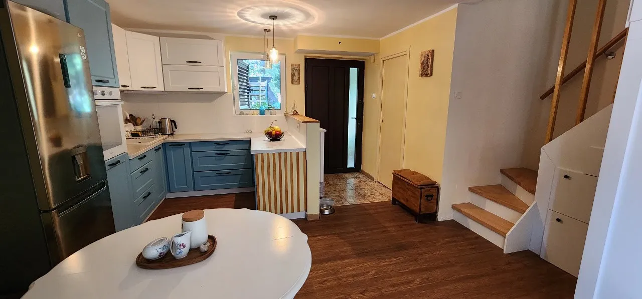 Kitchen with blue cabinets, stainless steel fridge, and white dining table in foreground.