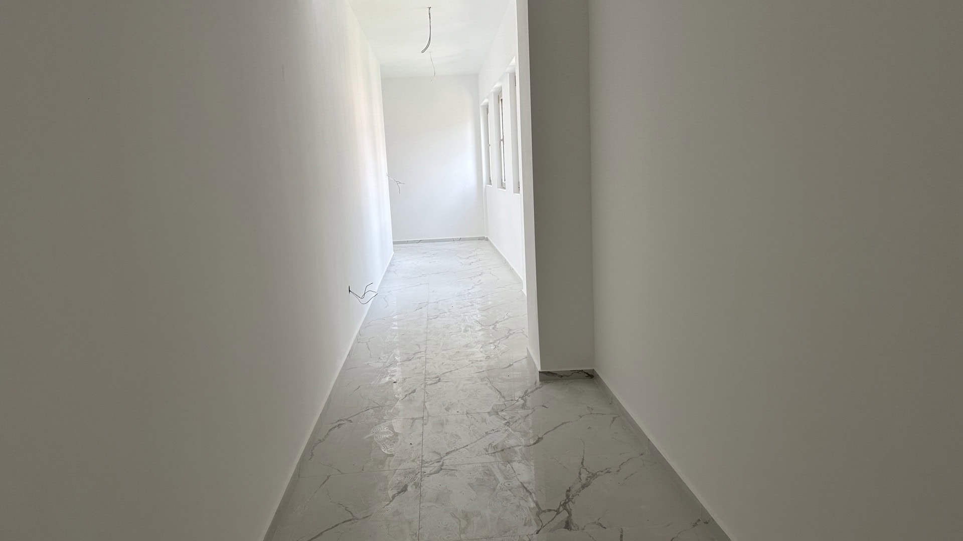 Bright hallway in a new apartment in Budva, Montenegro: white walls and marble-look porcelain tile flooring, pre-finished condition.