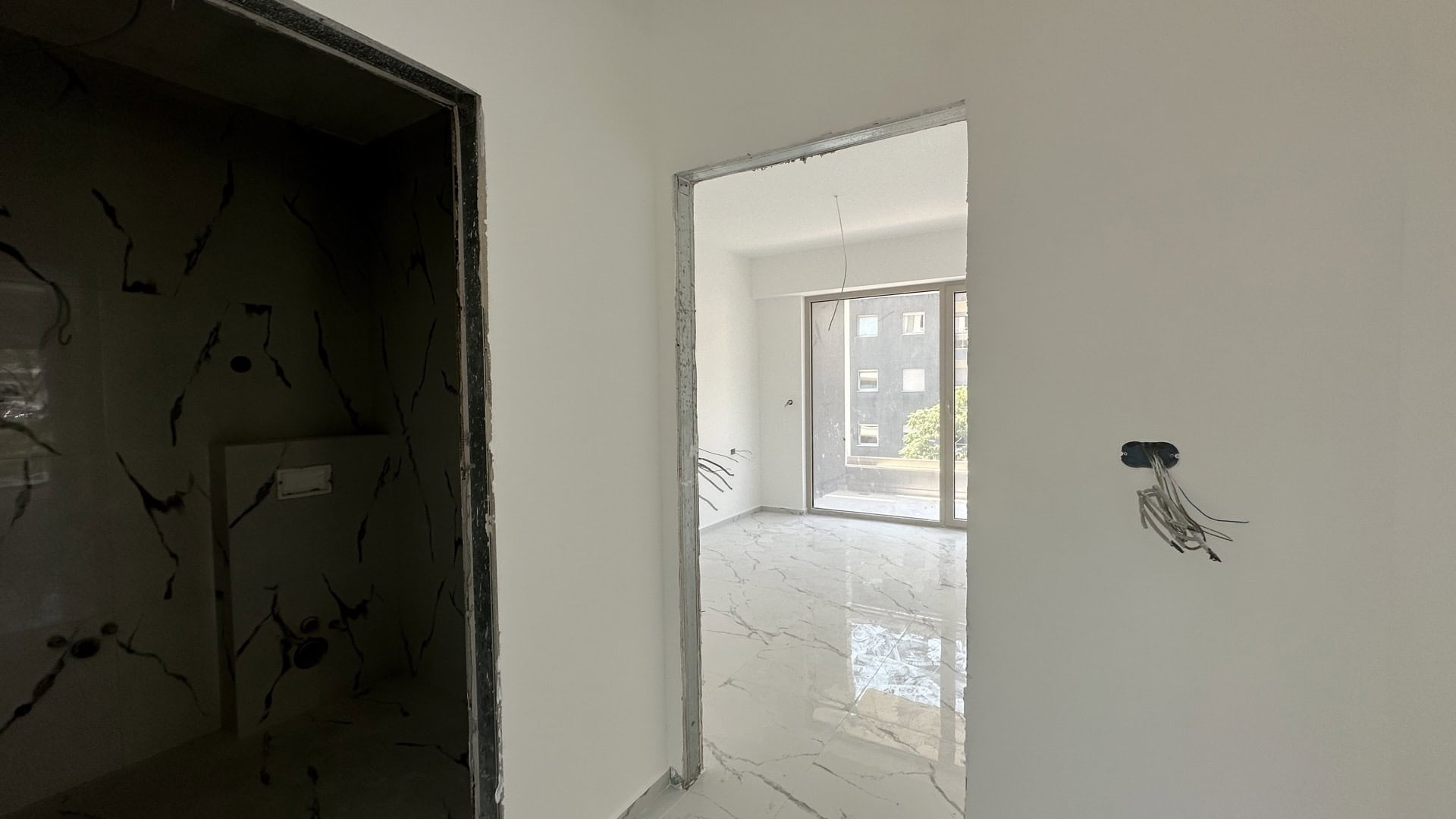 Apartment renovation in Budva, Montenegro: living room with marble floor and access to the balcony under finishing.