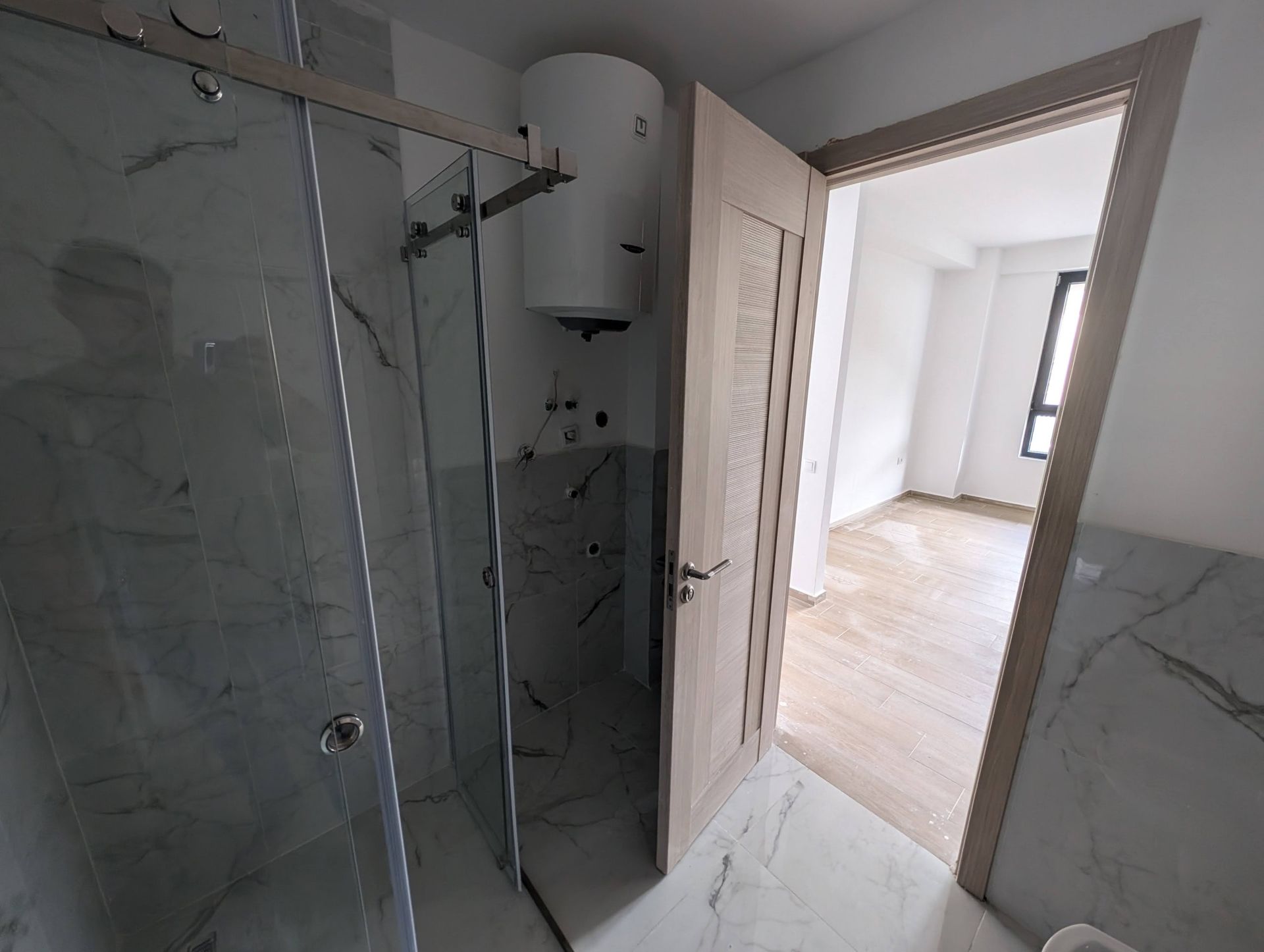 Modern bathroom with a shower cabin and water heater in a new construction apartment in Rafailovići, Montenegro.