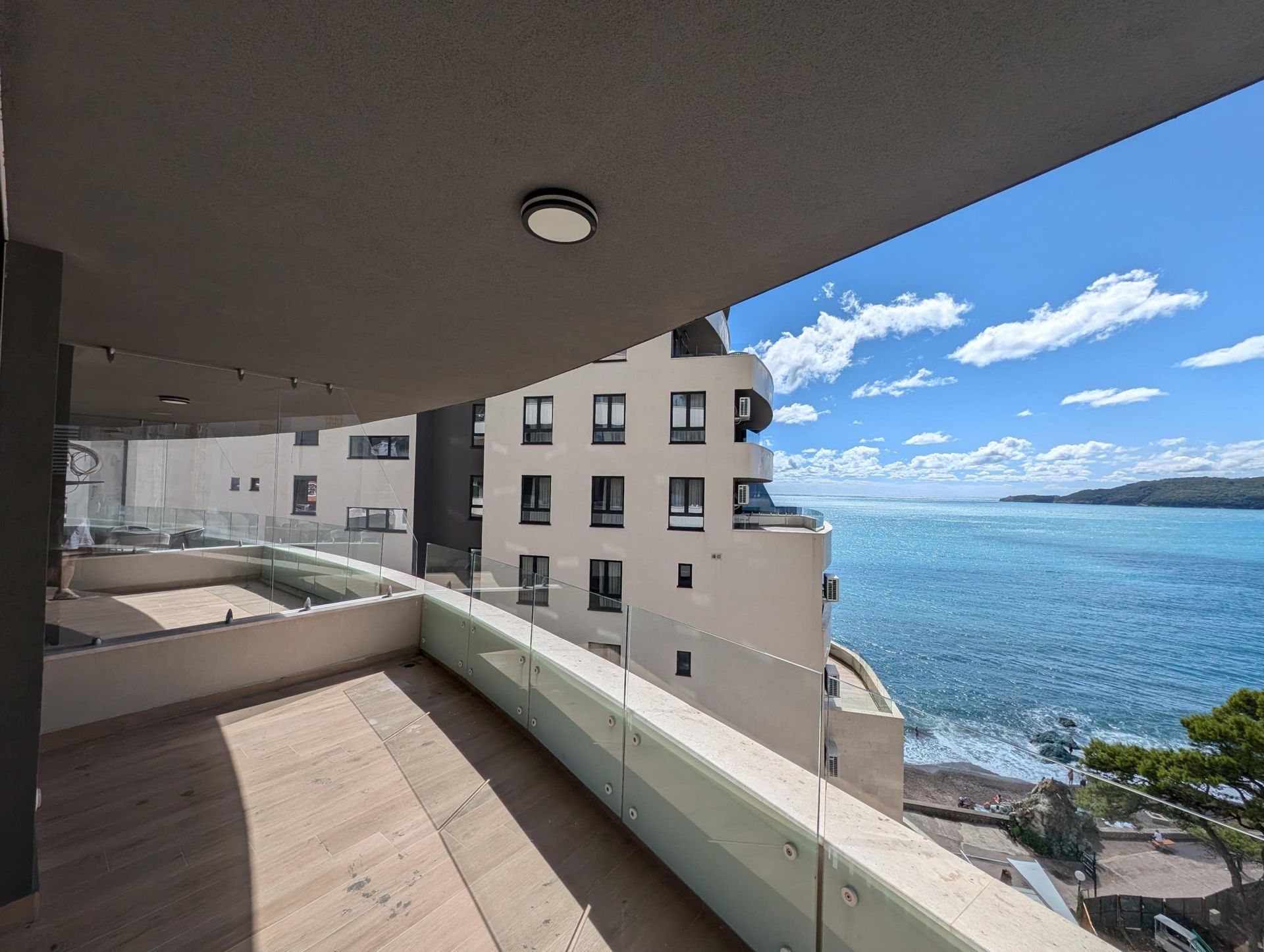 Spacious balcony with panoramic glass railing and sea view in Rafailovici, Montenegro