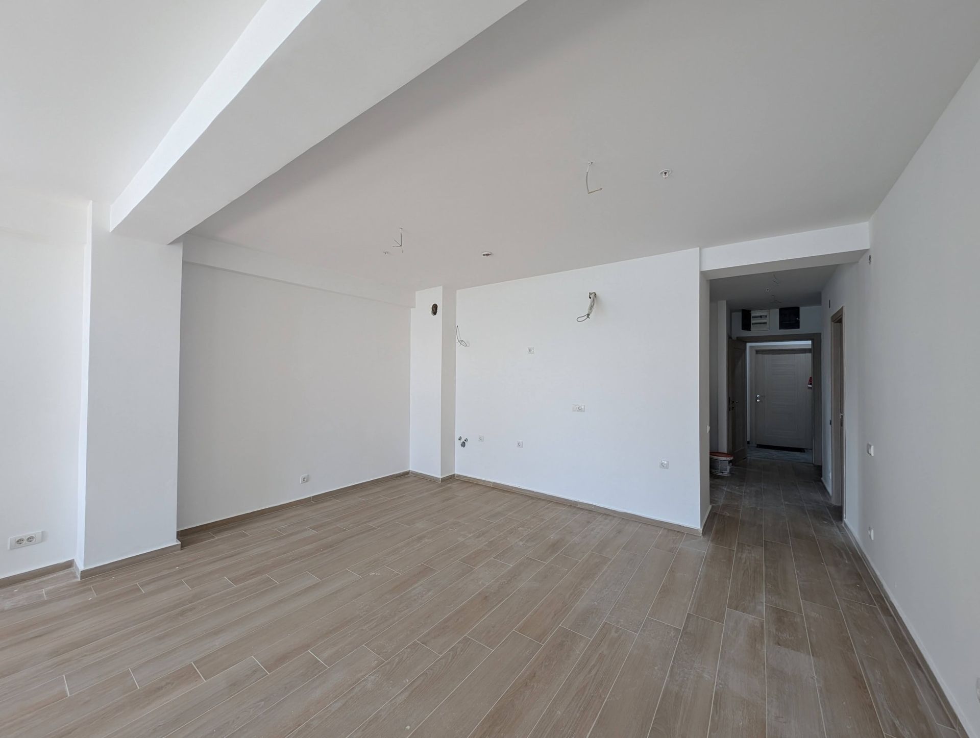 White living room in a new build in Rafailovici, Montenegro, with finished finishes, white walls, and wooden flooring.