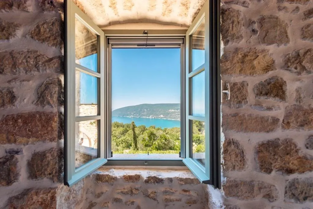 Open window in a stone wall overlooking the sea and hills. No interior room details visible.