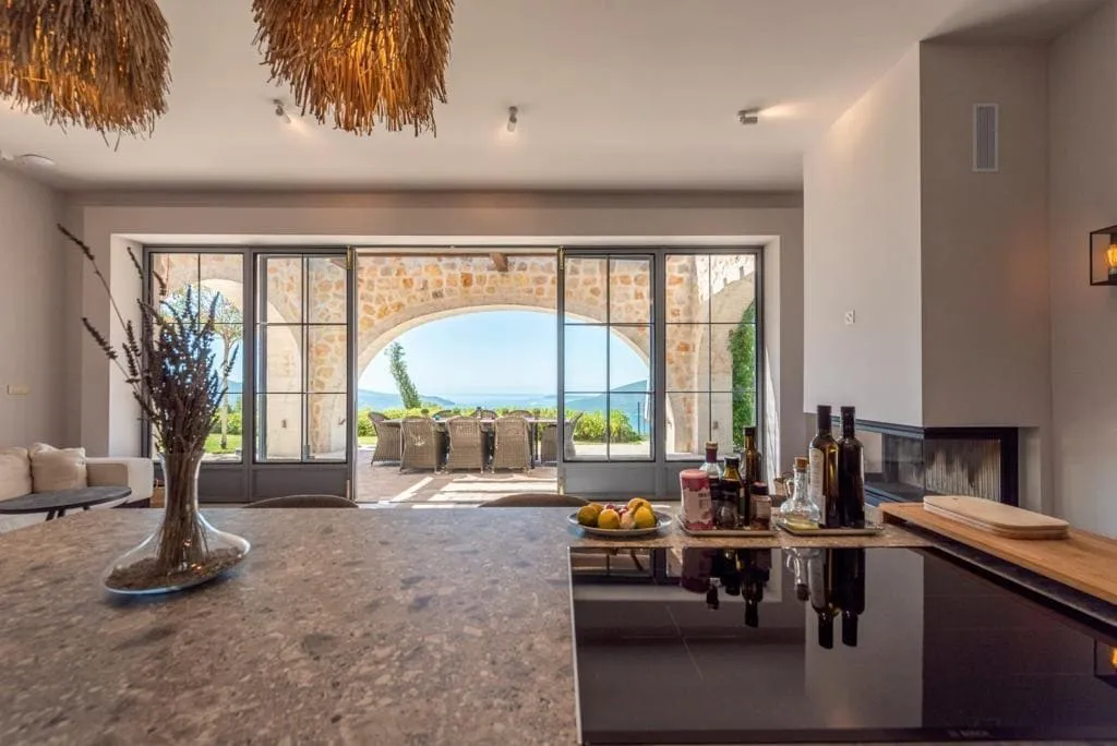 Kitchen counter with cooktop, straw pendant lights, and a view of the terrace overlooking the sea.
