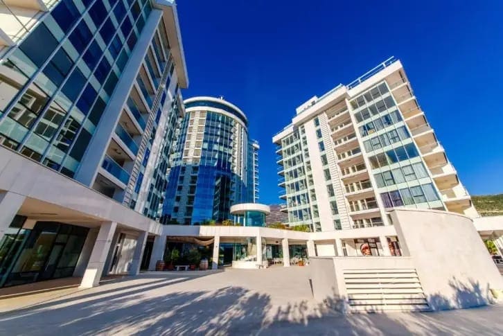 Modern residential complex with panoramic glazing in Budva, Montenegro: view of the facade and landscaped grounds.