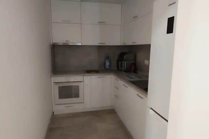 Modern white kitchen in an apartment in Budva, Montenegro: built-in appliances, glossy fronts, and light finishes.