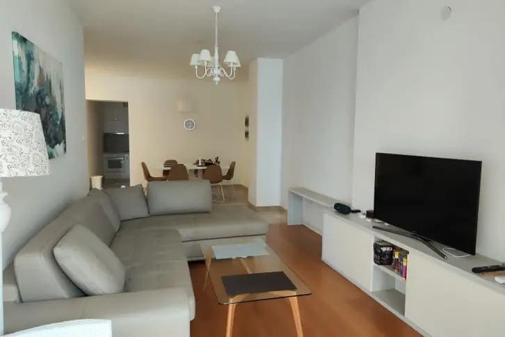 Bright living room with a gray corner sofa and dining area in an apartment, Budva, Montenegro.