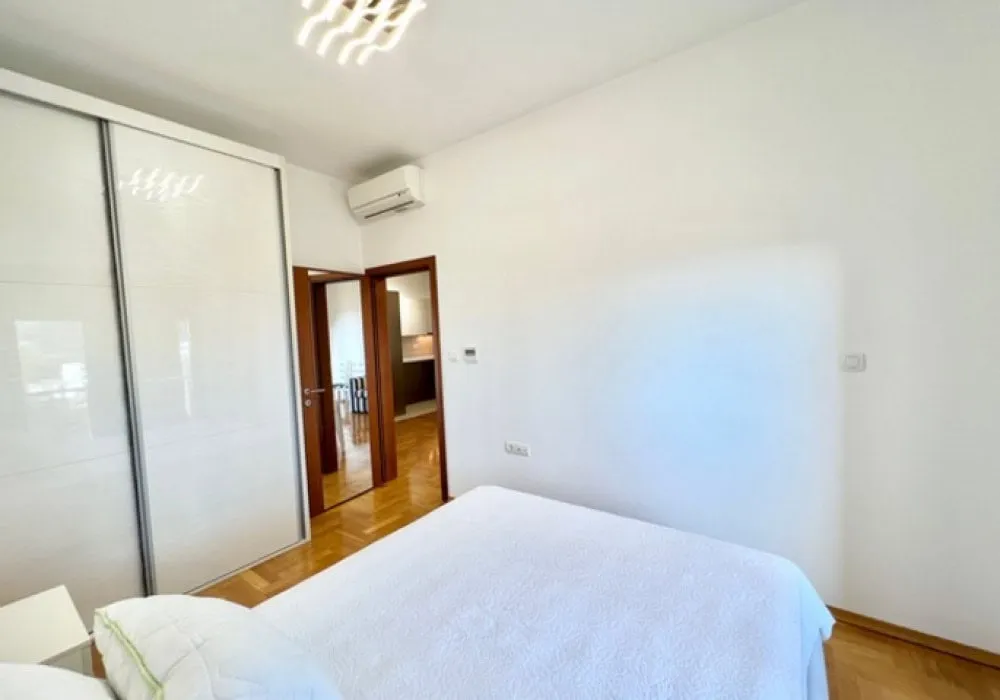 Bedroom featuring a white bed, large sliding wardrobe, and wall-mounted air conditioner.