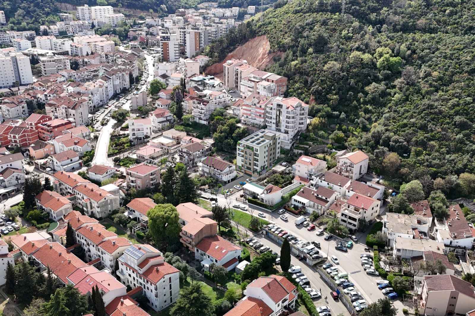 Aerial view of a densely built-up area with residential buildings and a green mountain in Budva, Montenegro.