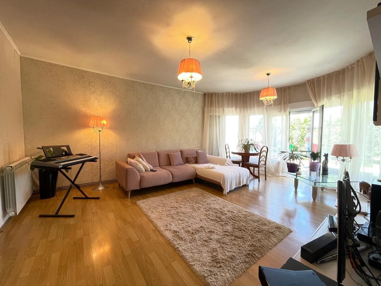 Cozy living room with a pink sofa and terrace access in a house, Bar, Montenegro. Bright interior with parquet flooring.