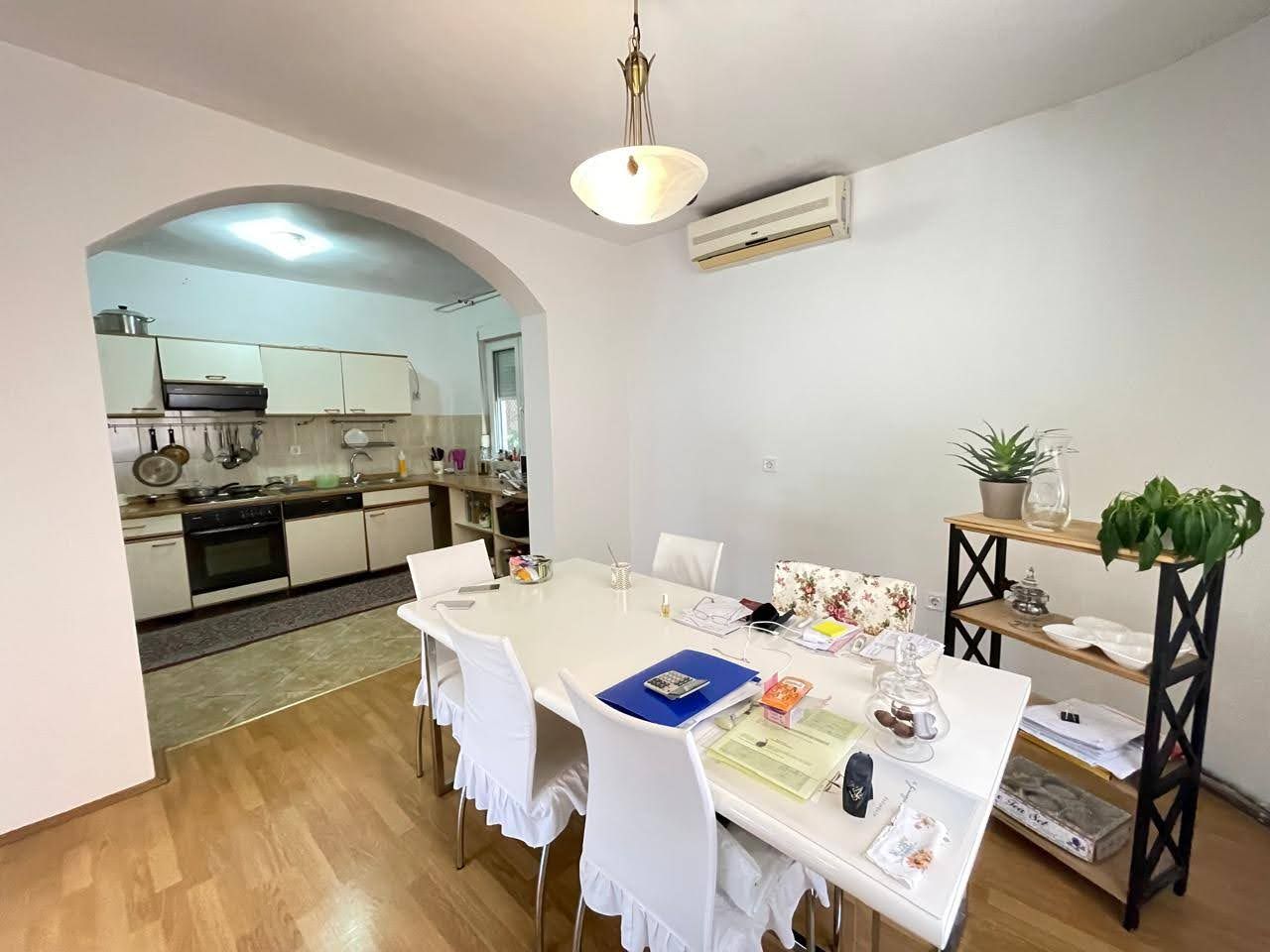 Living room with dining area and kitchen in a house, city of Bar, Montenegro: light furniture, arched doorway, and air conditioner.