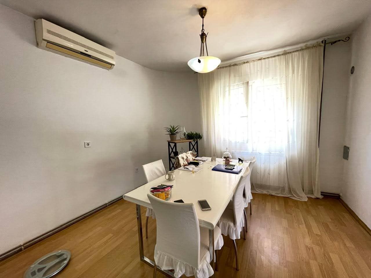 Bright living room with dining area in a house in Bar, Montenegro: white table, chairs, and air conditioner.