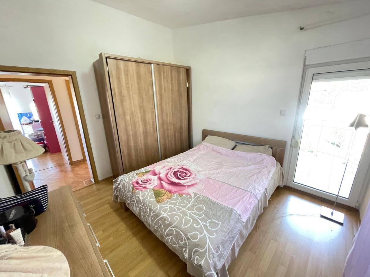 Bright bedroom with a double bed and wardrobe in a house for sale, Bar, Montenegro. View of the balcony and hallway.