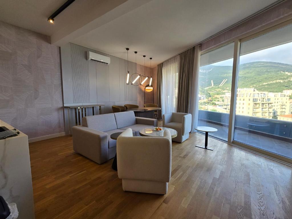Modern living room with panoramic windows and mountain views in an apartment in Bečići, Montenegro: stylish furniture and parquet flooring.